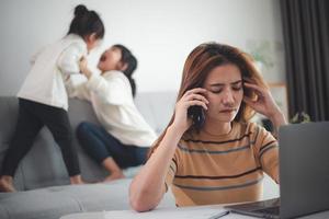 oficina en casa. trabajar desde casa frente a mamá con dos hijos trabajar en Internet en una computadora portátil en casa. cuarentena. coronavirus. foto