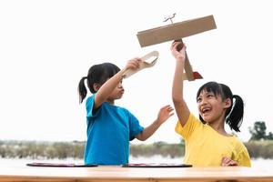 Two little kids playing with cardboard toy airplane in the park at the day time. Concept of happy game. Child having fun outdoors. photo