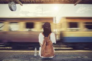 Traveler woman walking and waits train on railway platform photo