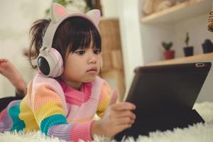 A Happy Asian little girl listening to music in the living-room photo