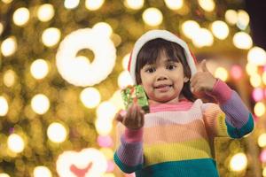 Happy child in Santa red hat holding Christmas presents. Christmas time. photo