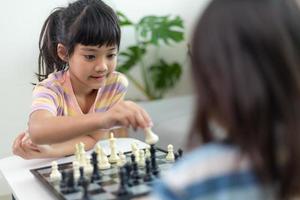 Little sibling girl playing chess at home. photo