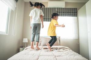 Two little girls jumping on bed when playing together photo