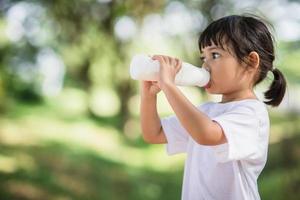 Cute asian little child girl is drinking a milk, soft focus photo