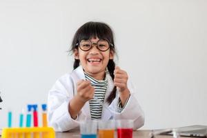 education, science, chemistry and children concept - kids or students with test tube making experiment at school laboratory photo