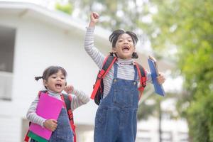 Children with rucksacks jumping in the park near school. Pupils with books and backpacks outdoors photo