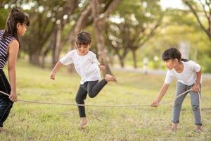 Happy kids playing together with jumping rope outdoors photo