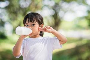 Cute asian little child girl is drinking a milk, soft focus photo