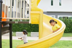 Child playing on outdoor playground. Kids play on school or kindergarten yard. Active kid on colorful slide and swing. Healthy summer activity for children. photo