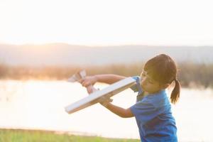 dreams of flight child playing with toy airplane against the sky at sunset photo