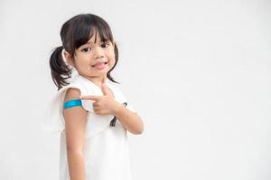 Asian little girl showing his arm after got vaccinated or inoculation, child immunization, covid delta vaccine concept photo
