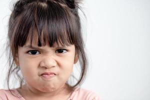 Angry little girl over white background, sign and gesture concept photo