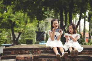 Concept kids and gadgets. Two little girls siblings sisters look at the phone. They hold a smartphone watch videos, learn, play games, speak online. Internet for children. photo