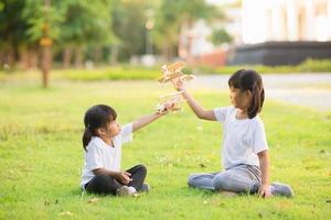 Two little kids playing with cardboard toy airplane in the park at the day time. Concept of happy game. Child having fun outdoors. photo