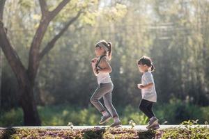 Two asian little girls having fun and running together in the park in vintage color tone photo
