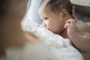 madre amamantando a su bebé recién nacido al lado de la ventana. la leche del pecho de la madre es una medicina natural para el bebé. concepto de unión del día de la madre. enfoque suave foto