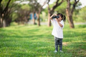 Happy child girl playing with binoculars. explore and adventure concept photo