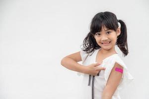 Asian little girl showing his arm after got vaccinated or inoculation, child immunization, covid delta vaccine concept photo