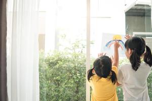 siblings girl drawing rainbow looks through the window during covid-19 quarantine. stay at home social media campaign for corona virus photo