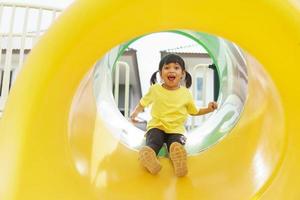 Child playing on outdoor playground. Kids play on school or kindergarten yard. Active kid on colorful slide and swing. Healthy summer activity for children. photo