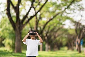 Happy child girl playing with binoculars. explore and adventure concept photo