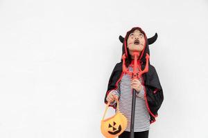 Asian child girl in demon costume holding black and red trident, Happy halloween concept photo