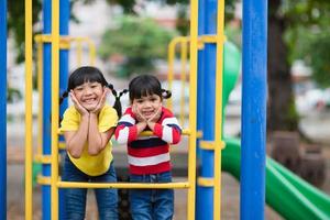 lindas niñas hermanos divirtiéndose en el patio de recreo al aire libre en un día soleado de verano foto