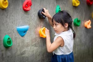 little girl climbing a rock wall photo