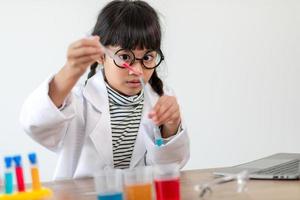 education, science, chemistry and children concept - kids or students with test tube making experiment at school laboratory photo