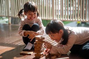 two Asian girls playing wooden stacks at home photo