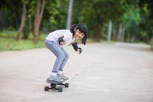 Cute little girl playing skateboard or surf skate in the skate park photo