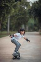 Cute little girl playing skateboard or surf skate in the skate park photo