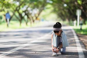 Kid tying running shoes. Happy Funny little asian girl fitness woman running at morning . Athletic young child running in the nature. Healthy lifestyle photo