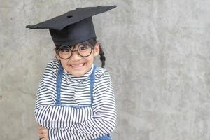 feliz niño de la escuela asiática graduado en gorra de graduación foto