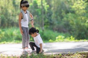 Cute asian girl give hand to help sister accident during running photo