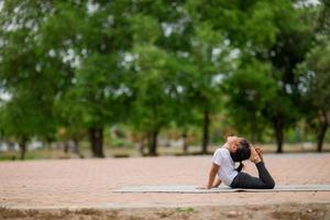 Little cute asian girl practicing yoga pose on a mat in park, Healthy and exercise concept photo