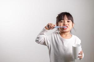 Little cute child girl brushing her teeth on white background. Space for text. Healthy teeth. photo