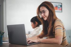 Mother working from home and taking care of her daughter too. photo