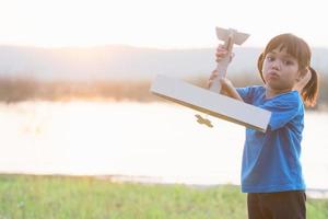 dreams of flight child playing with toy airplane against the sky at sunset photo