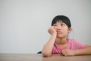 asian child rest her cheeks on the fists with moody face photo