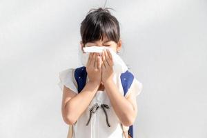 Asian child girl sick with sneezing on the nose and cold cough on tissue paper because weak or virus and bacteria from dust weather photo