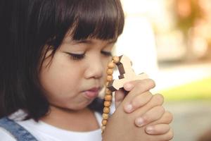 Little Asian girl praying with holding the cross, Christian concept. photo