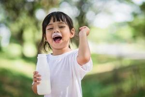 Cute asian little child girl is drinking a milk, soft focus photo