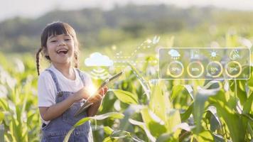 The little girl uses a tablet to analyze the growth of plants in the agricultural plot and visual icon., the agricultural technology concept. smart farming learning Concept photo