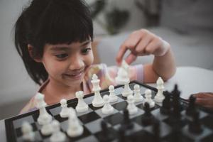 pequeña hermana jugando al ajedrez en casa. foto