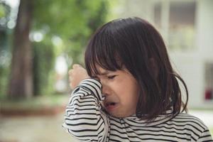 Portrait of Asian crying little girl with little rolling tears weeping emotion, hurt in pain fit drops cheek. Young crying panic drama Asian toddler. photo