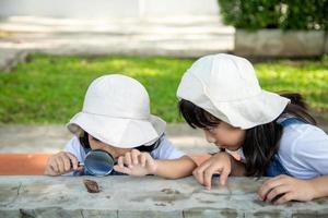 Happy kid girl exploring nature with a magnifying glass and a snail. He having fun in the garden. The concept of the kid is ready to go to school. photo