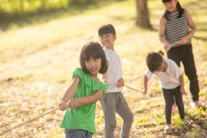 Children playing tug of war at the park on sunsut photo