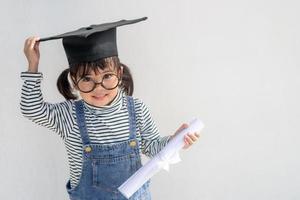 Happy Asian school kid graduate in graduation cap photo