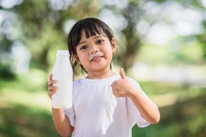 Cute asian little child girl is drinking a milk, soft focus photo